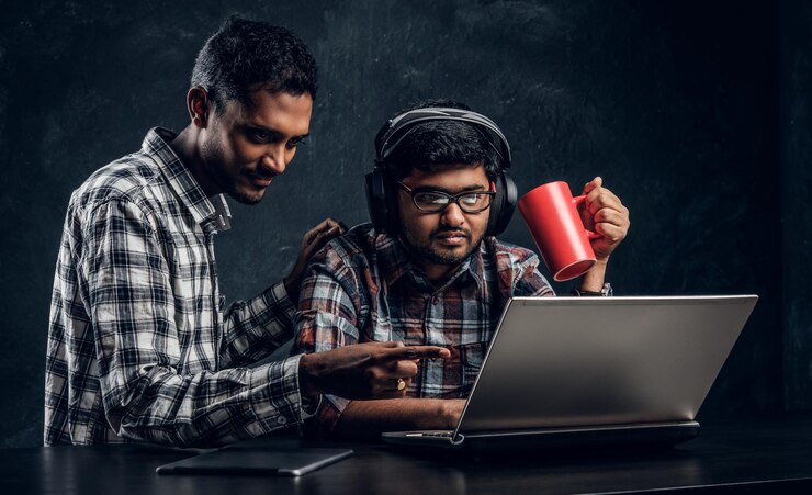 Two Indian Student Friends Working Together New Project Sitting Table With Laptop Against Dark Textured Wall 613910 20909